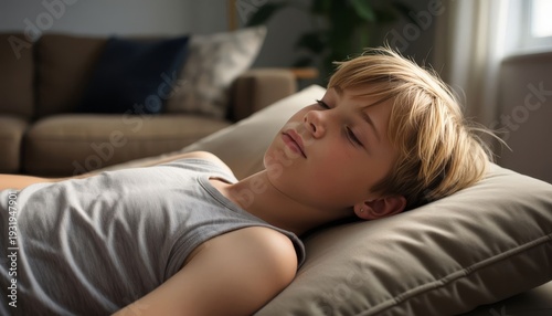 A boy is lying on a couch, resting peacefully on a pillow. The boy looks calm and undisturbed in a cozy living room setting.