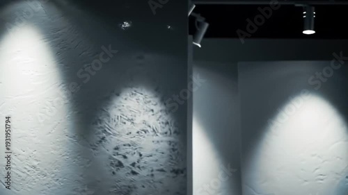 Spotlights illuminate textured walls in a modern art gallery space.