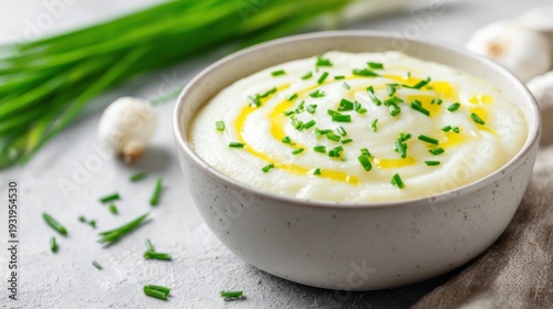 A comforting bowl of creamy cauliflower soup garnished with fresh chives and a swirl of olive oil