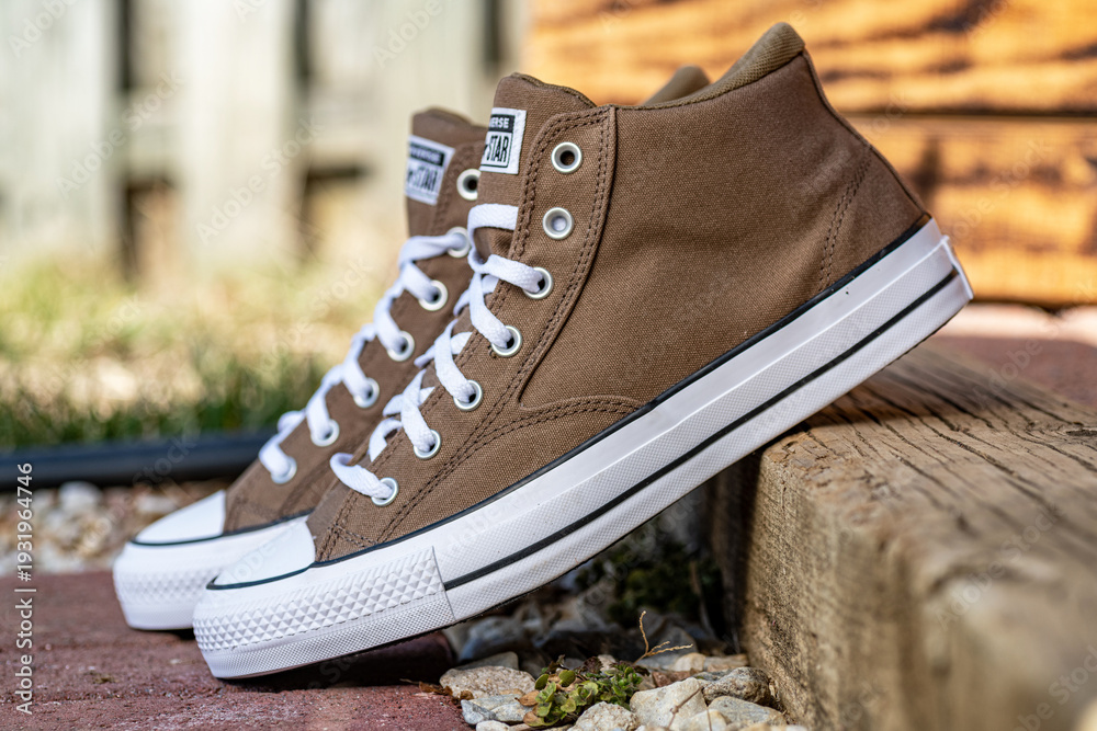 Obraz premium Brown Converse Chuck Taylor high top sneakers on wooden step outdoors