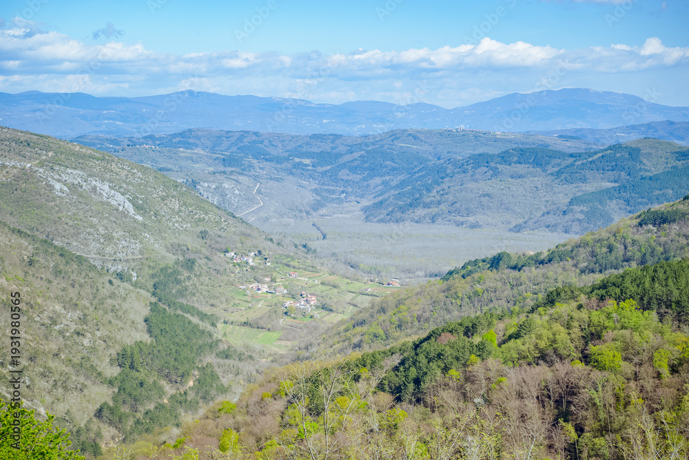 Fototapeta premium Oprtalj, Istria, Croatia: Mountain valley with village and forest under blue sky