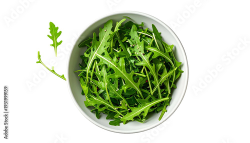 Overhead shot of fresh, green leafy arugula in a white bowl, against a black background