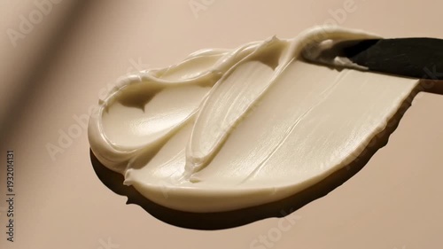 Organic shea butter spread in abstract wave patterns across a matte beige background, top-down studio shot emphasizing organic curves and subtle ridges formed by a palette knife, diffused window light