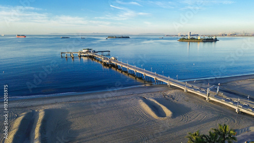 Pier and twin islands view from Belmont Veterans Memorial Pier faces harbor channel with Island Chaffee and Island Freeman visible offshore. Calm water, warm coastal haze, Long Beach, California