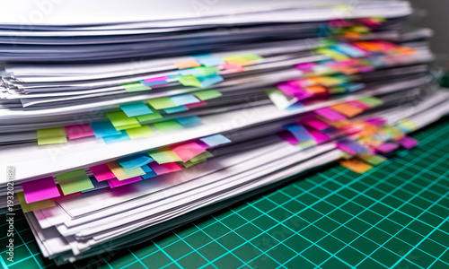 organized office paperwork pile with vibrant rainbow index tabs on a green grid surface background