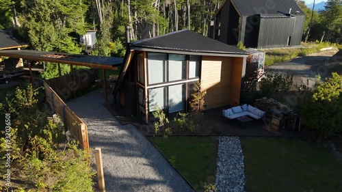 Luxury cabin with contemporary A-frame architecture, nestled in a lush forest with mountain views and a landscaped garden.