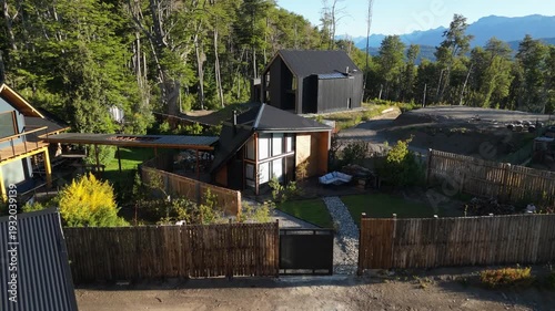 Modern luxury cabin with contemporary A-frame architecture, nestled in a lush forest with mountain views and a landscaped garden.