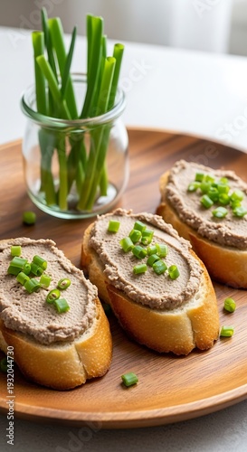 Delicious Liver Pate Crostini with Fresh Chives on Wooden Plate.