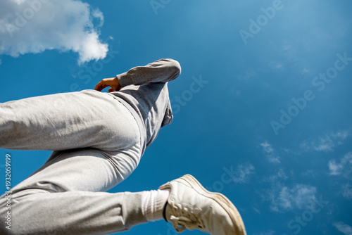 Young man running under a bright blue sky with clouds