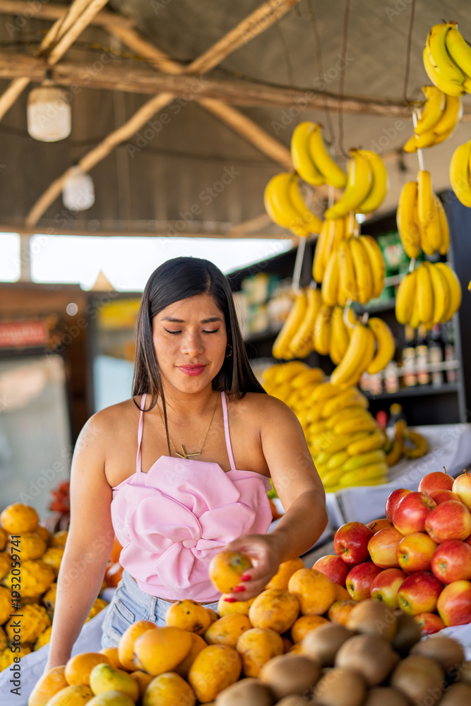 Obraz premium Woman selecting fresh fruit at local market stall