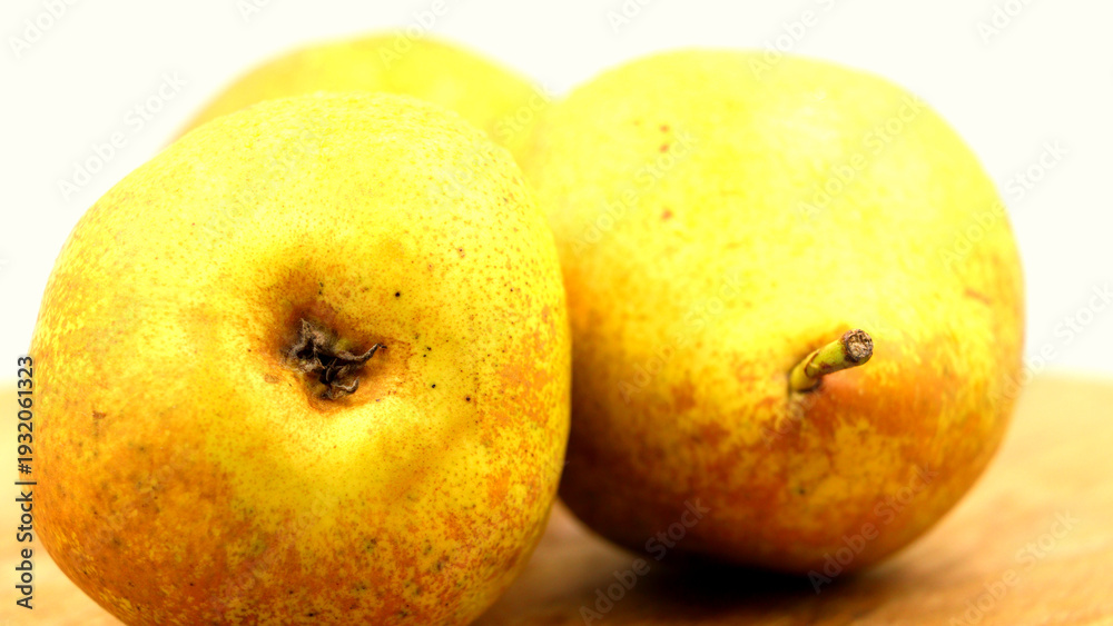 Fototapeta premium Three ripe golden pears on a bright background.