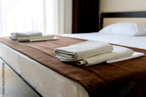 Neatly arranged towels on bed with brown blanket in hotel room