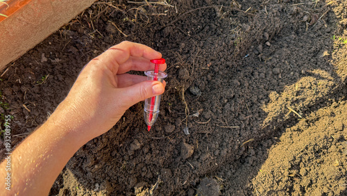 Foto A hand tenderly places a vibrant red vial in the soil, celebrating Earth Day's r
