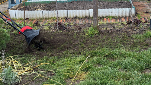 Billede på lærred Electric tiller churns the damp earth, whispering secrets of spring planting and