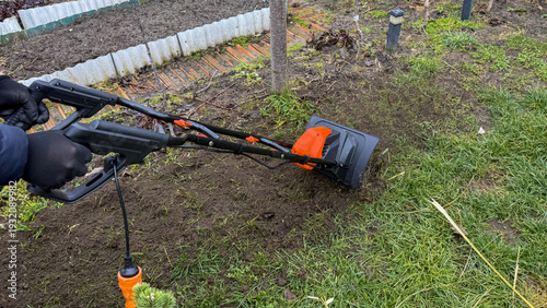 фотографія Digits wrapped in snug gloves guide the chugging orange cultivator through sprin