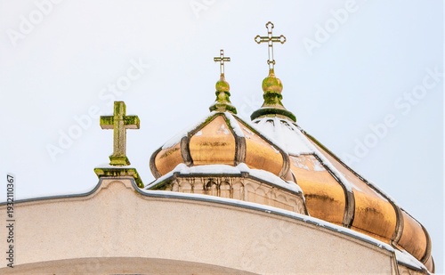 Obraz na plátně Golden domes topped with crosses gleam against a light sky, partially covered with snow