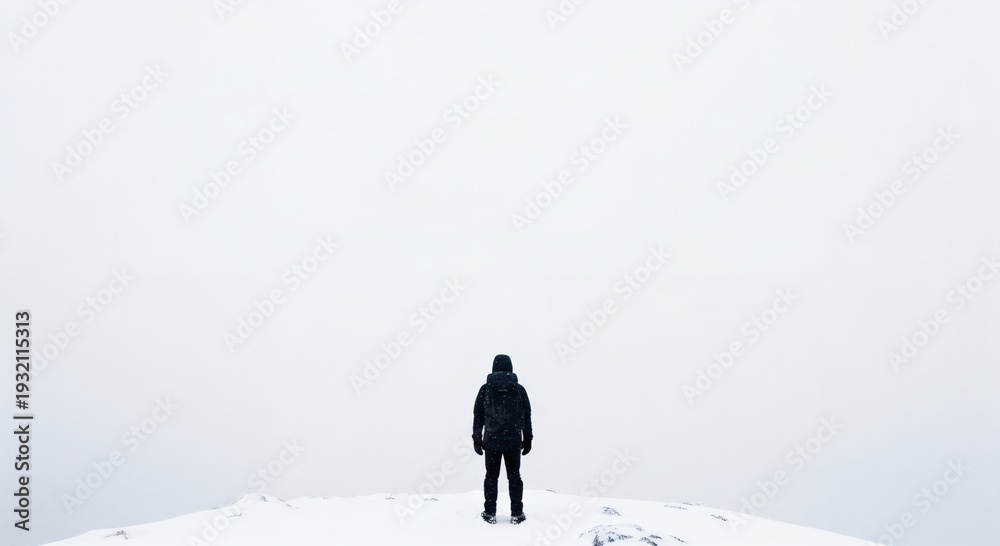Naklejka premium Lone Male Hiker Standing on a Snowy Mountain Peak in a Whiteout, Back View of a Man in Winter Gear Facing a Vast White Horizon