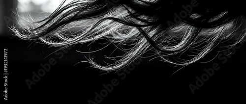 Flowing dark hair strands in motion against black background creating dynamic movement and texture for beauty and fashion concepts.