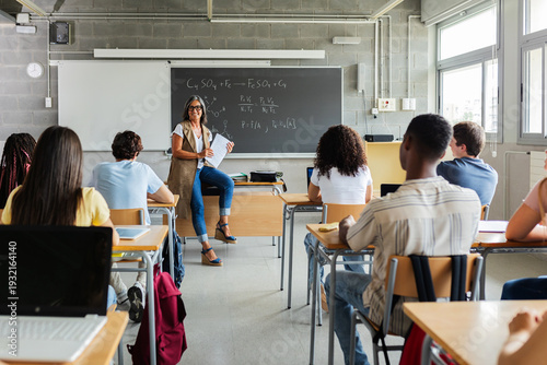 Young student group attending lesson with teacher in classroom. Diverse people learning during an academic lesson in a high school setting. Education and teaching concept.