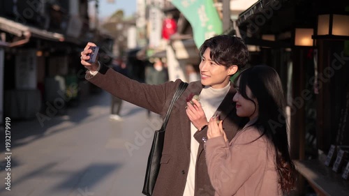 柴又の観光地でスマートフォンで自撮りするカップル