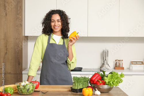 Young happy African-American woman with vegetables and bell peppers for fresh...
