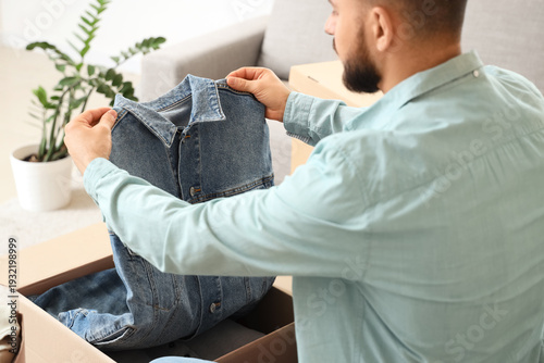 Young man unpacking cardboa...
