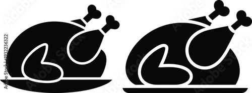 Two black and white roasted turkeys with drumsticks on serving platters style