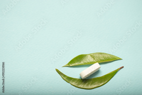 Minimal healthcare concept with pills and green leaves on blue background