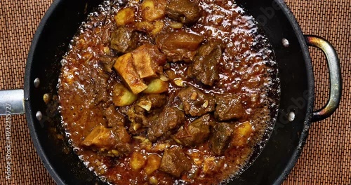 Beef curry cooking sizzling bubbling in pan over hot flame top view flat lay top view 