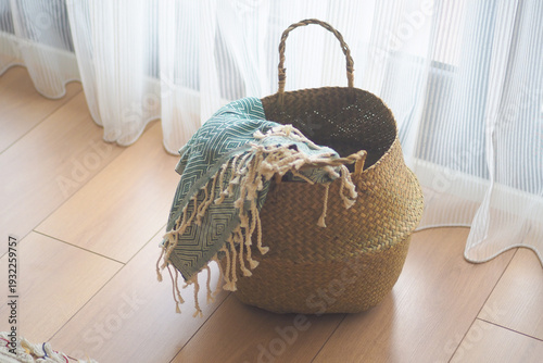 Cuadro en lienzo Blanket draped over woven basket by window in a room