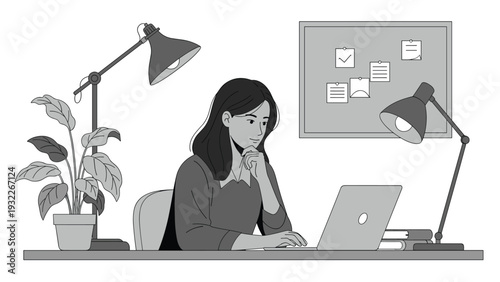 Focused young woman sitting at her home office desk while working on a laptop surrounded by lamps and office supplies.