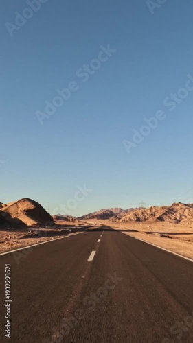 Vertical shot of pov driving through asphalt desert road with rocky slopes on roadside at sunset