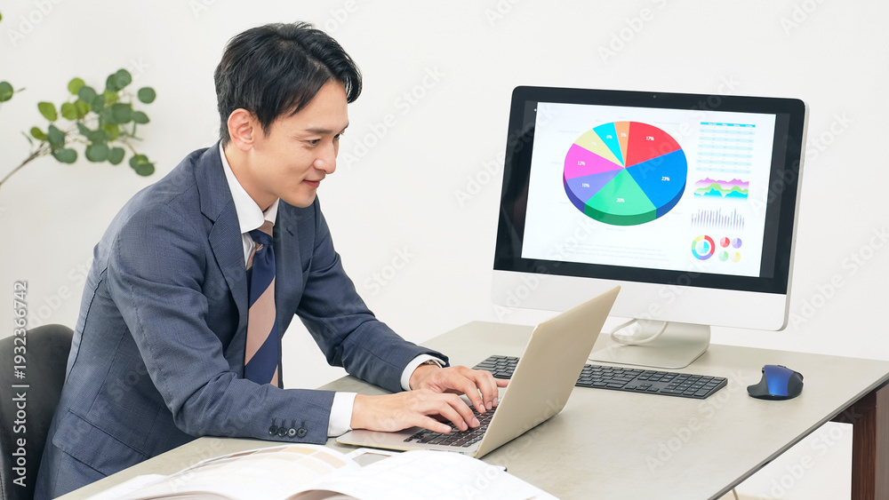 Fototapeta premium オフィスでPCを見ながら仕事する男性ビジネスパーソン