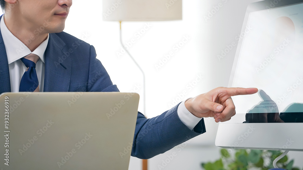 Obraz premium オフィスでPCを見ながら仕事する男性ビジネスパーソン