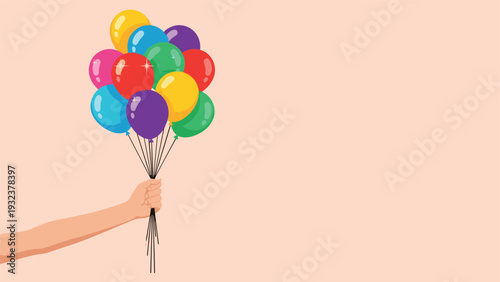 Human arm and hand holding a large bunch of vibrant colorful balloons against a soft peach background representing celebration and joy.