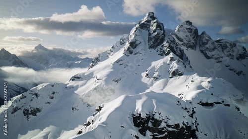 Snowy Mountain Peaks Under Blue Sky With Dramatic Clouds And Rugged Alpine Landscape
