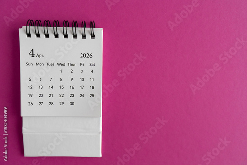 Desk calendar for April 2026 on a bright pink background.