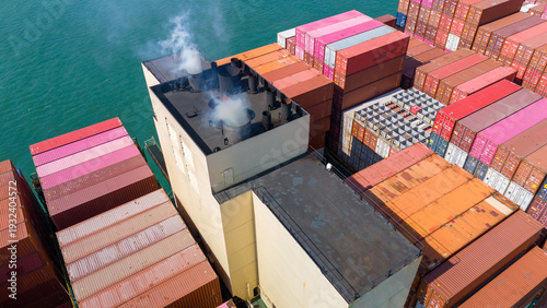 Fotografi container ship exhaust funnel emitting smoke while sailing on the ocean