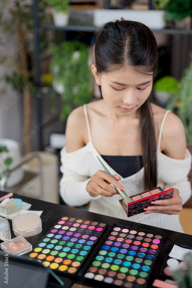 Fototapeta premium Asian woman applying make up foundation and concealer make up on face with cosmetics makeover Daily beauty routine at home.