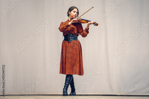 Принти на полотні young girl dressed in a brown dress stands on the stage and plays the violin