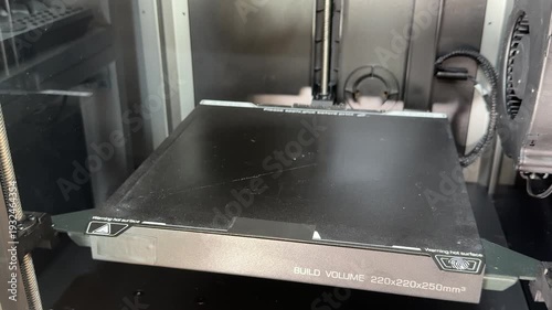 3D printer build plate rises along the vertical axis during setup, showing precise mechanical movement and calibration.