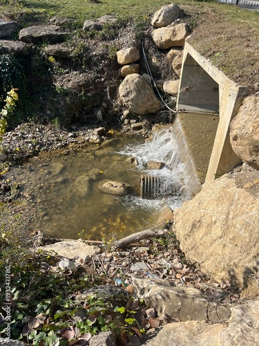Foto Concrete culvert discharging water into rocky creek.