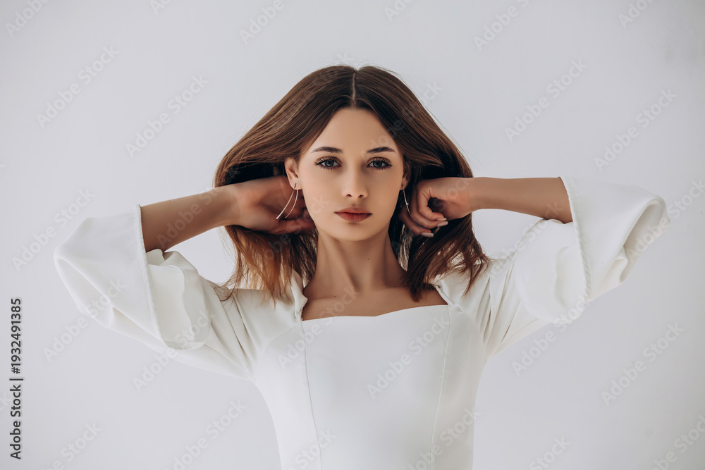 Naklejka premium Beauty portrait of a model, a beautiful brunette girl with straight long hair in a white dress, healthy and natural on a white background