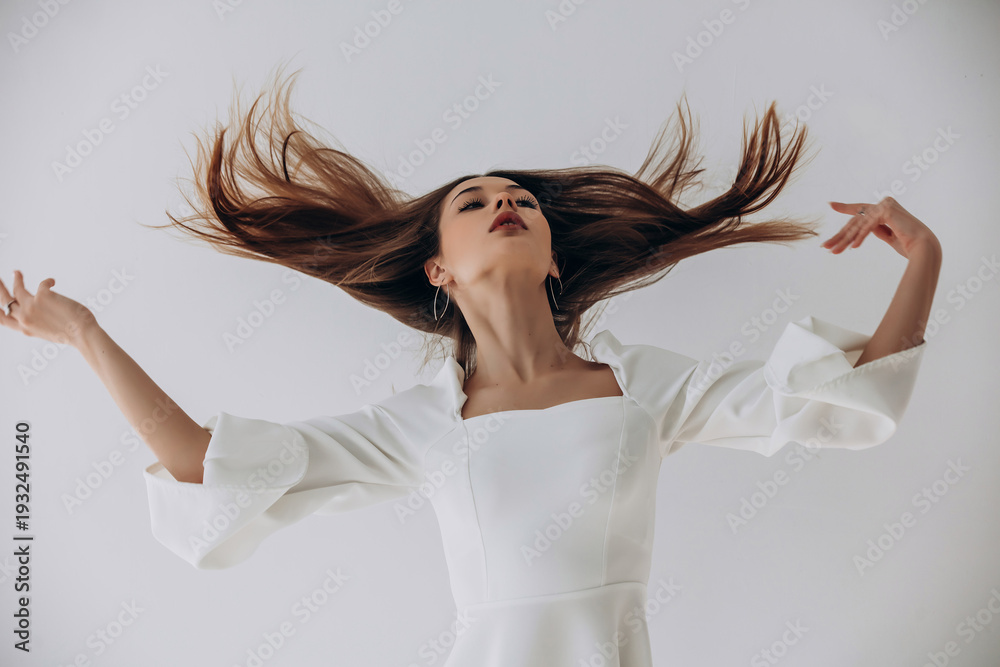 Naklejka premium Beauty portrait of a model, a beautiful brunette girl with straight long hair in a white dress, healthy and natural on a white background