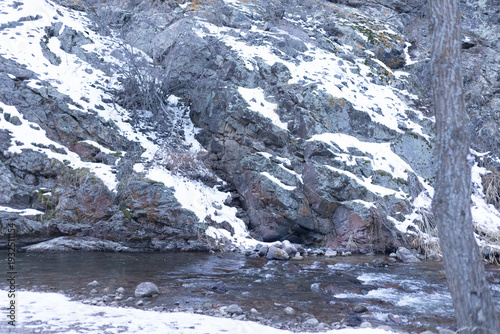 Frozen river bank with snow and rocks in winter