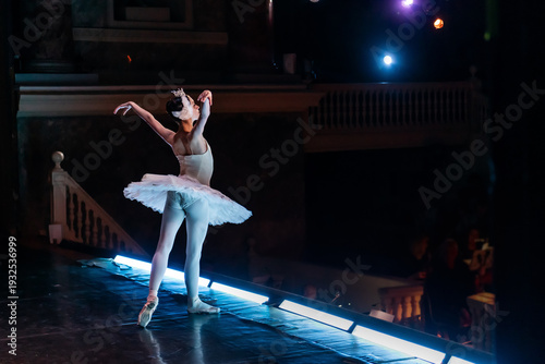Ballet soloist in white tutu bowing on stage toward audience