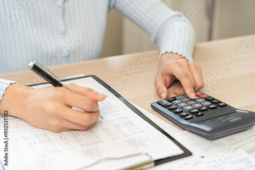 Foto Stressed person asian young employee woman hand using calculator to calculate expenses of monthly and checking expenses from bill, receipt on table at home