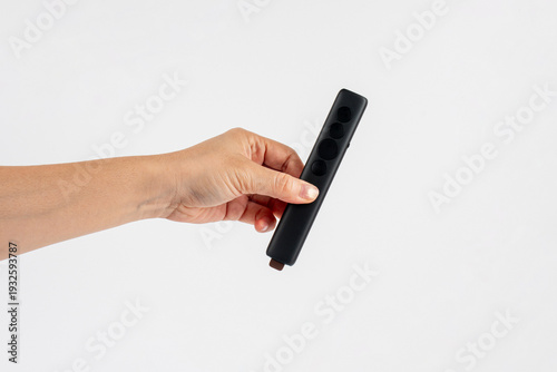 Wallpaper Mural A small black remote control in a hand, against a white background. Torontodigital.ca