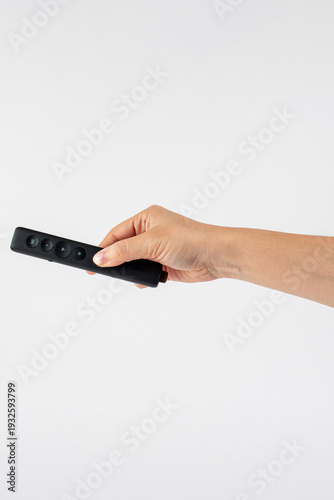 Wallpaper Mural A small black remote control in a hand, against a white background. Torontodigital.ca