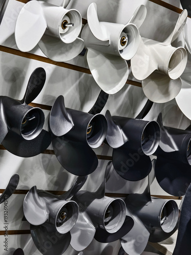 Different types of boat propellers displayed on a wall for sale in a shop specializing in marine equipment and accessories